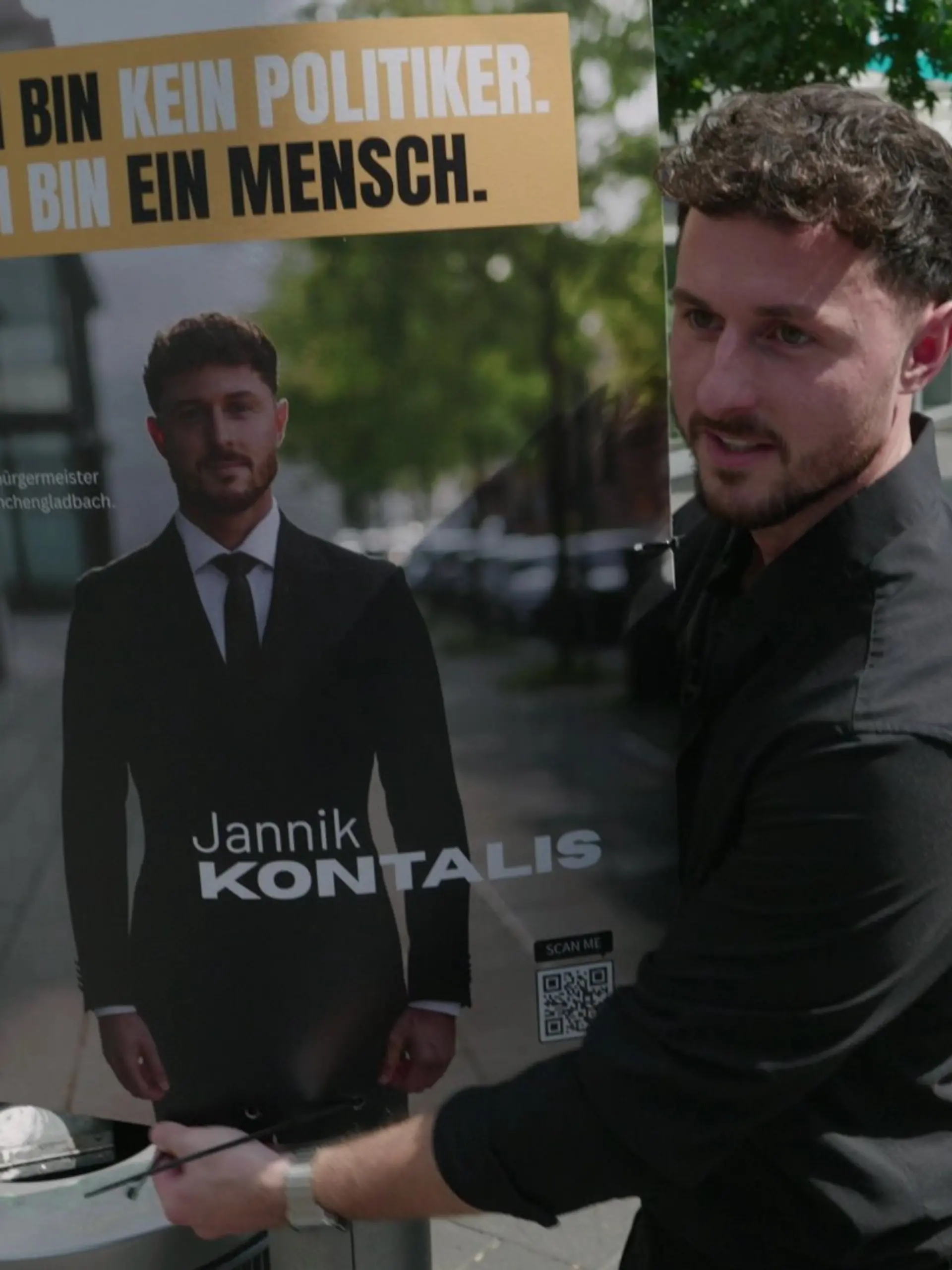 Jannik Kontalis hängt ein Wahlplakat auf.