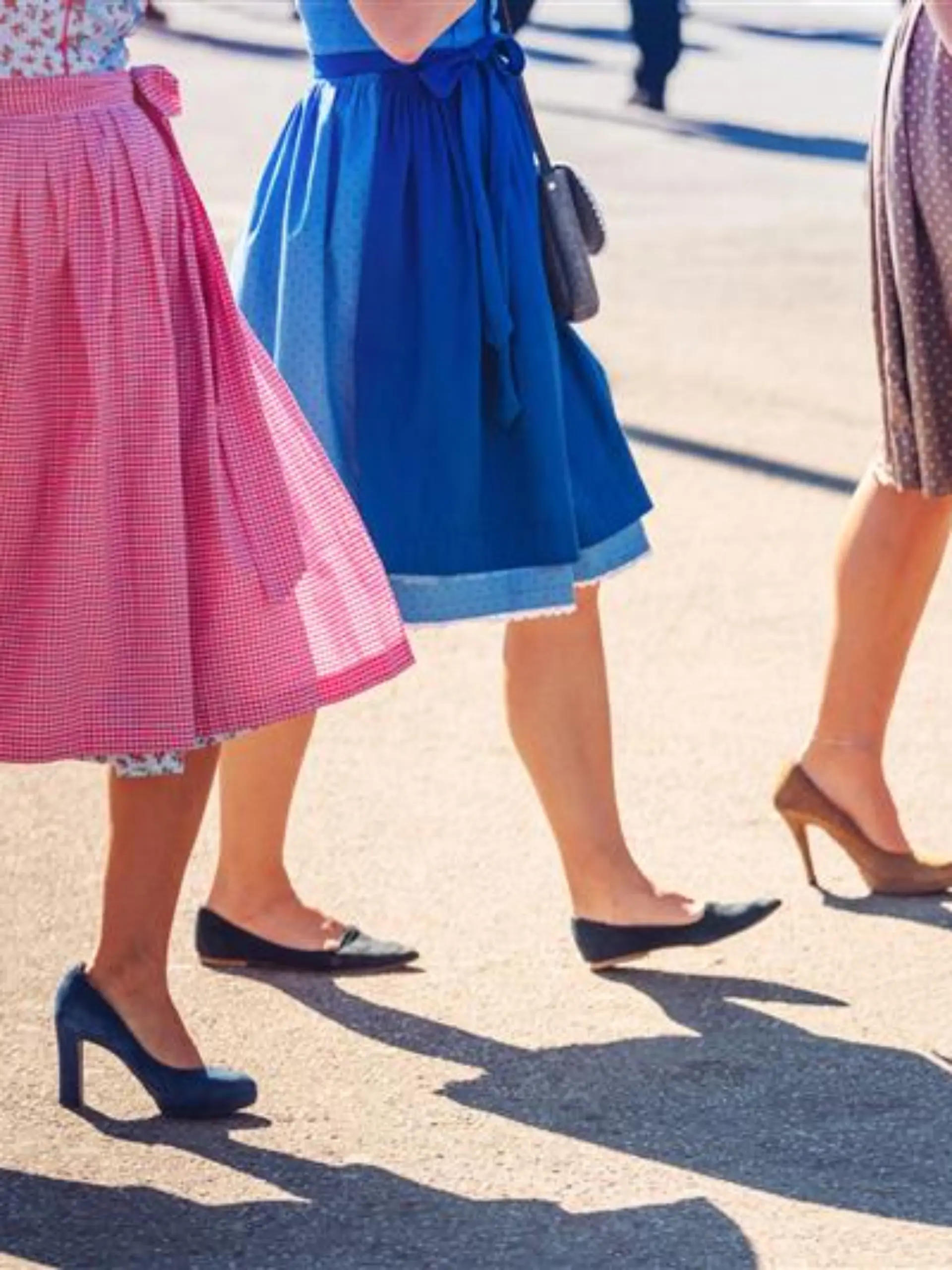 Drei Frauen tragen bunte Dirndl. 