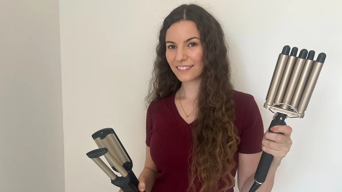 RTL-Reporterin Isabelle Kurz hat gewellte Haare und hält zwei Welleneisen in ihren Händen.