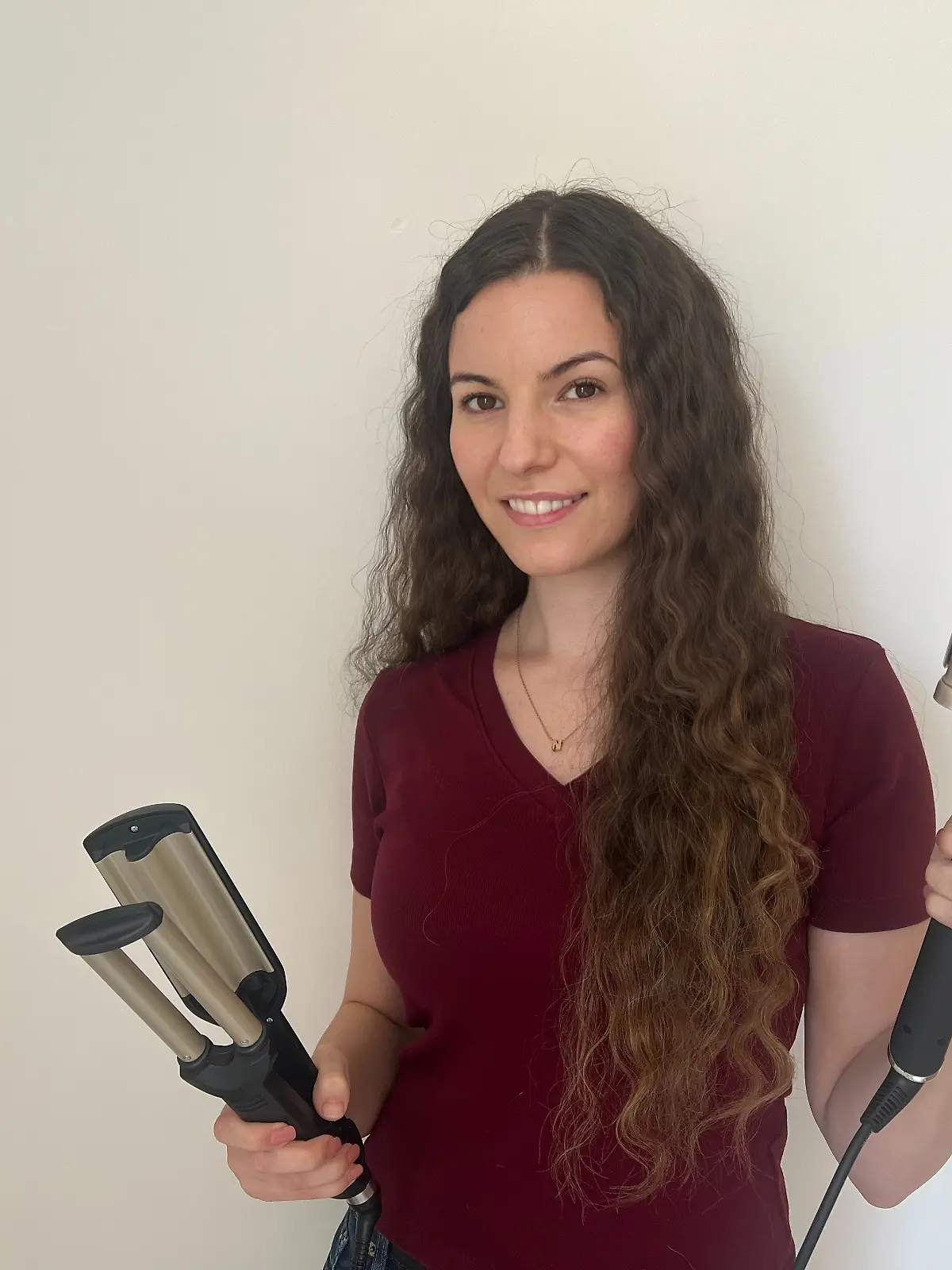 RTL-Reporterin Isabelle Kurz hat gewellte Haare und hält zwei Welleneisen in ihren Händen.