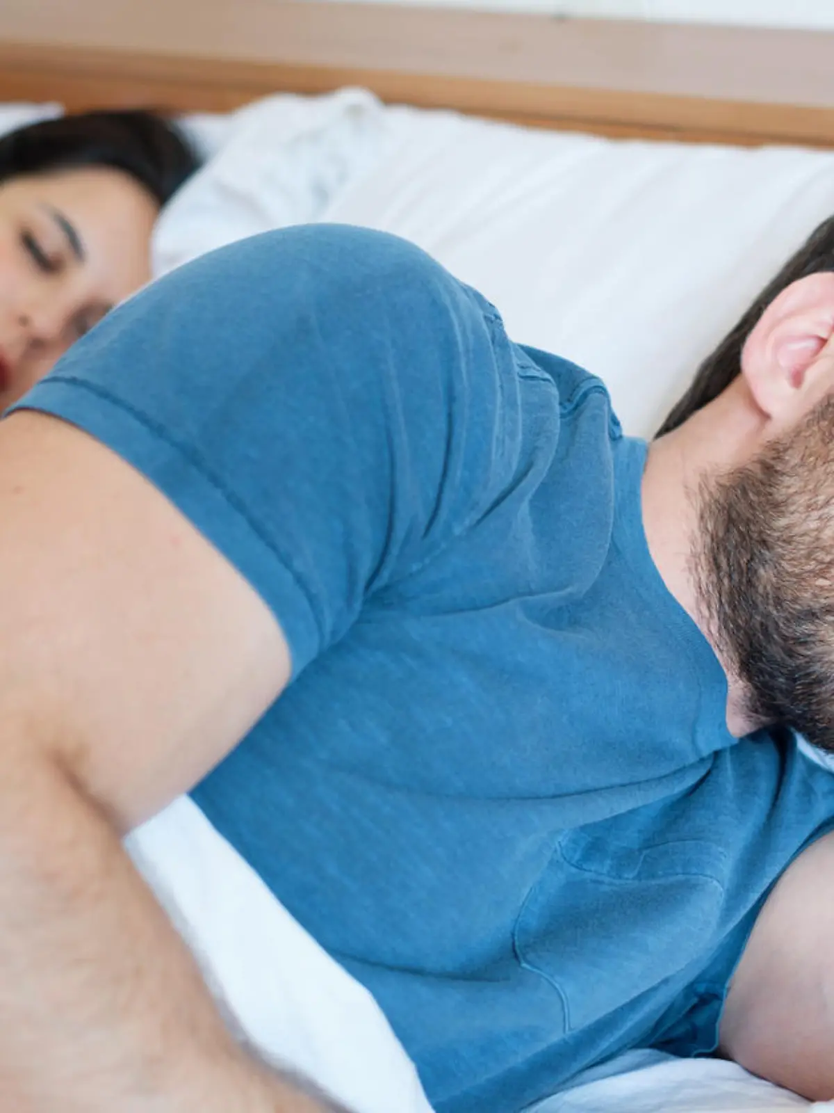 Depressed young man lying in bed and having problems with his girlfriend
