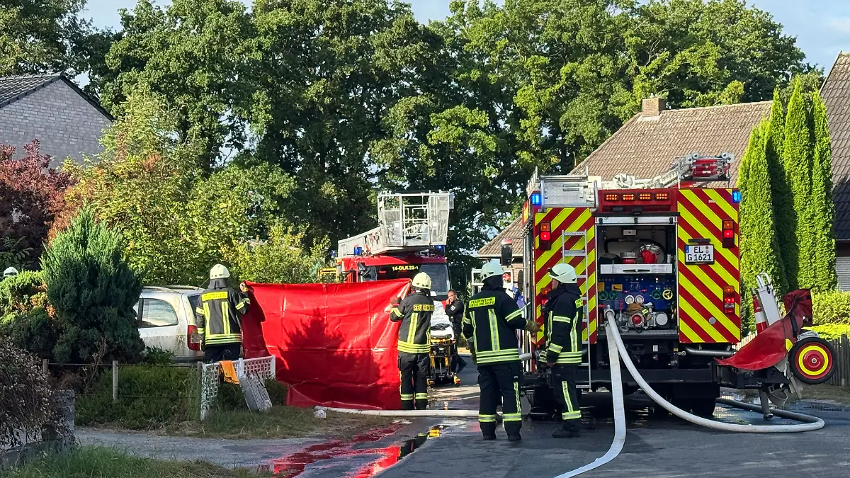 Einsatzkräfte der Feuerwehr stehen nach einem Wohnungsbrand im Landkreis Emsland vor einem Mehrfamilienhaus. Bei dem Wohnungsbrand ist ein Mann ums Leben gekommen. 