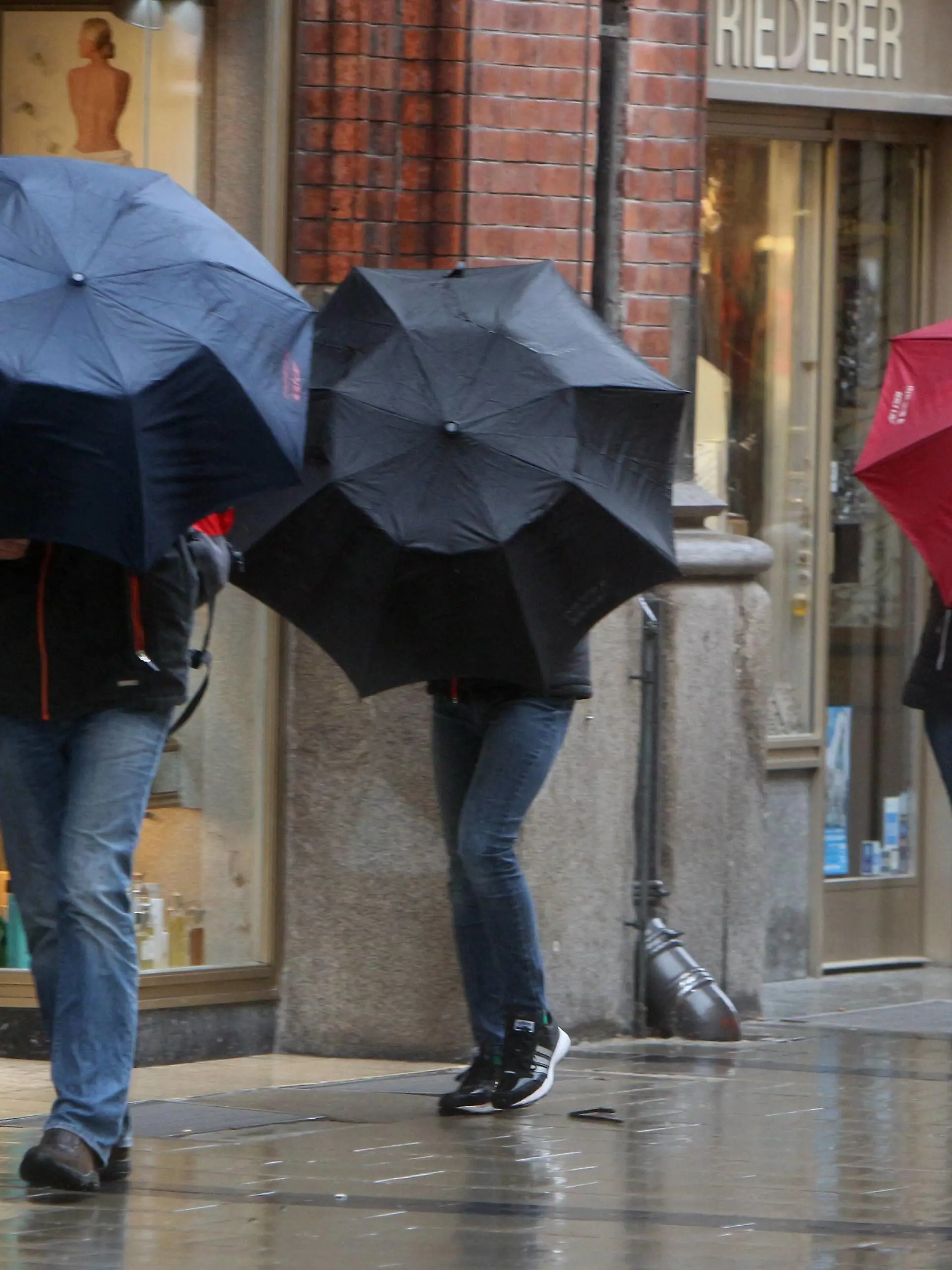Ein Tiefdruckgebiet sorgt für Orkanböen und Regen in der Innenstadt München, Bayern, Deutschland: Personen kämpfen mit ihren Regenschirmen am Marienplatz *** A low-pressure area causes hurricanes and rain in downtown Munich Bavaria Germany People fight with their umbrellas at Marienplatz  