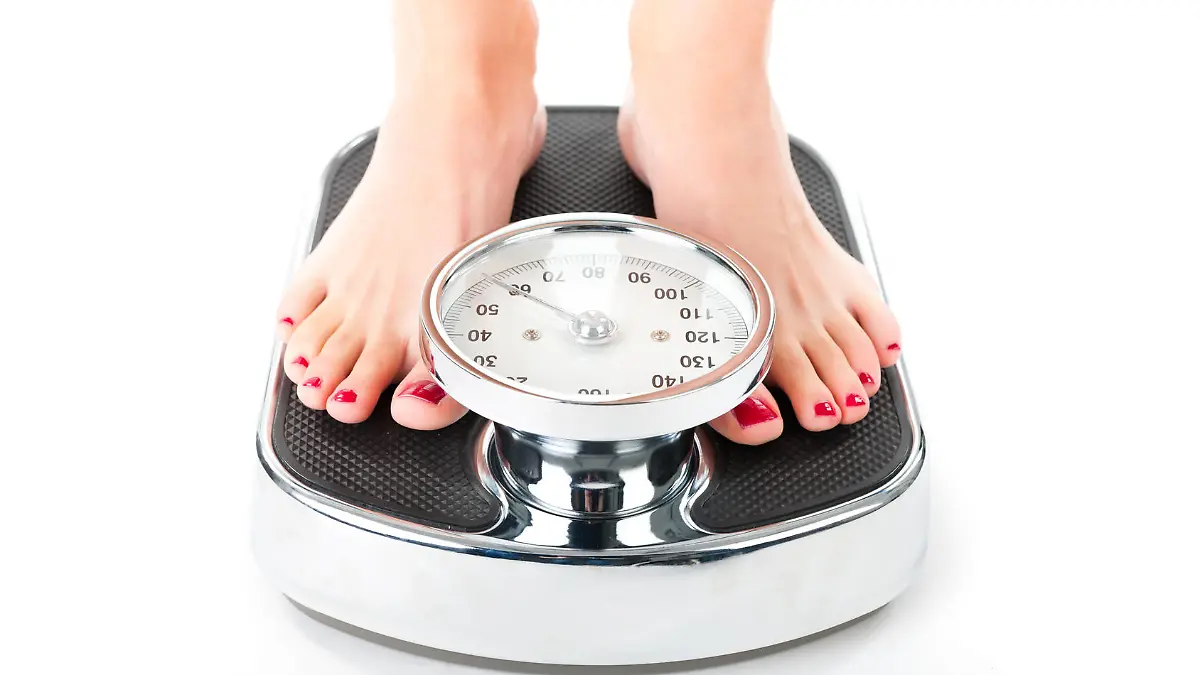 Diet and weight, young woman standing on a scale, only feet to be seen