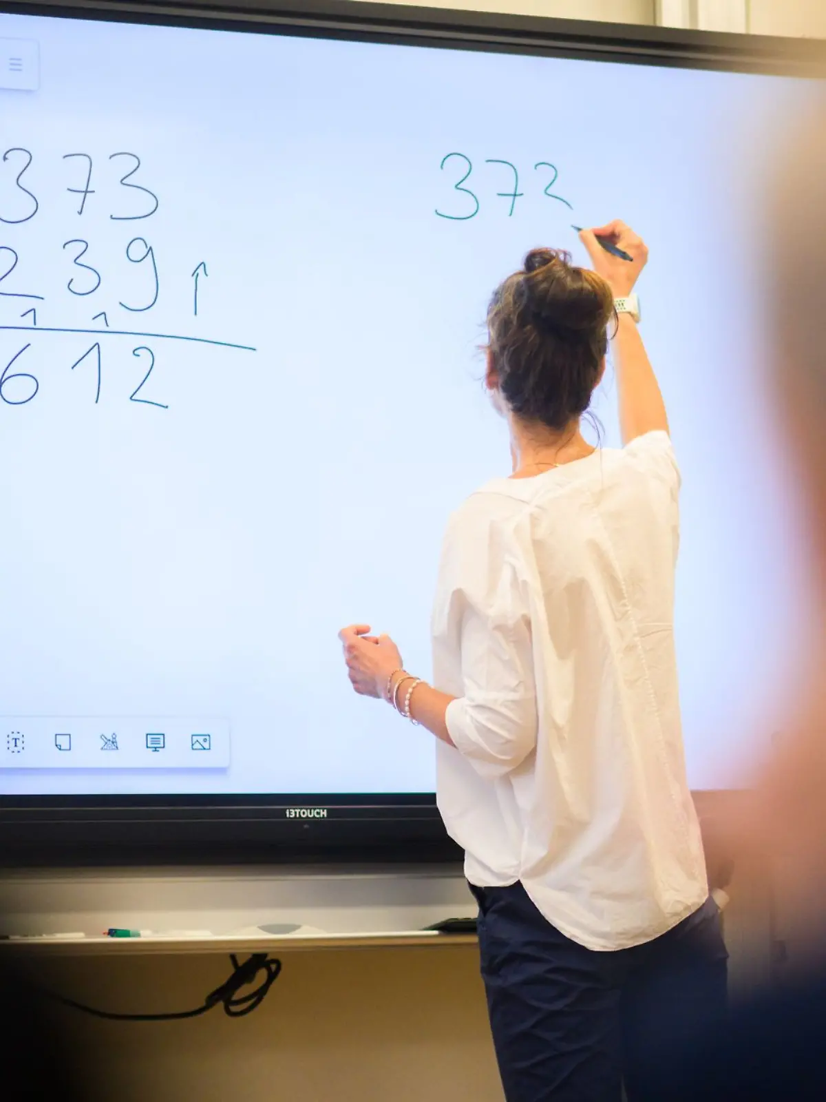 Eine Lehrerin steht an einer Tafel im Unterricht