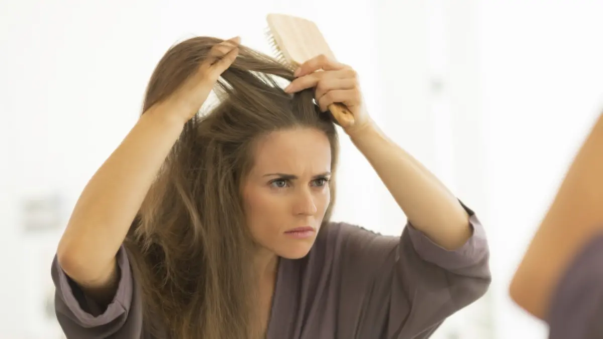 Concerned young woman combing hair in bathroom
