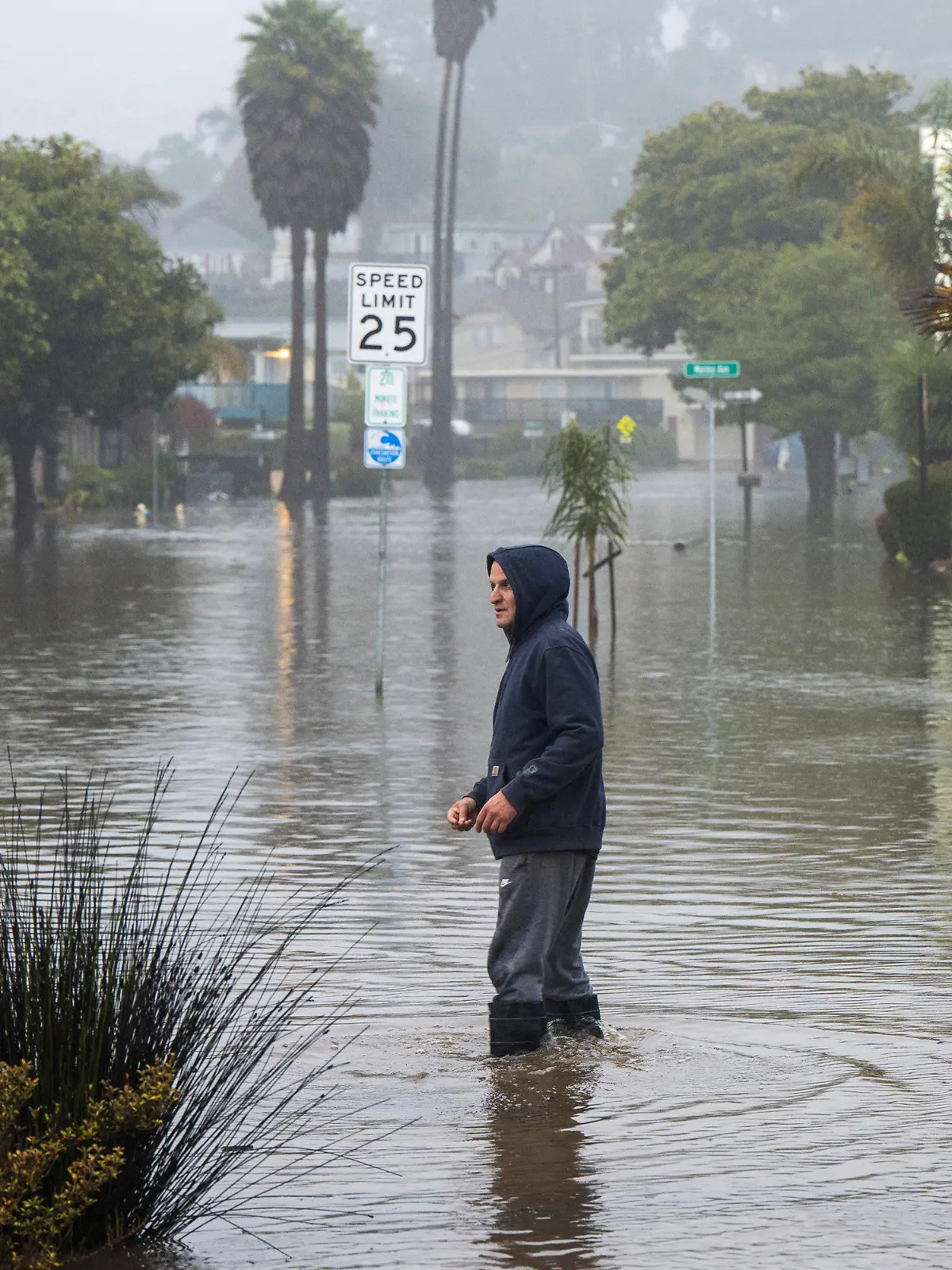 09.01.2023, USA, Aptos: Ein Mann watet durch eine überschwemmte Straße in der Nähe von Rio Del Mar. Foto: Nic Coury/FR171100 AP/dpa +++ dpa-Bildfunk +++