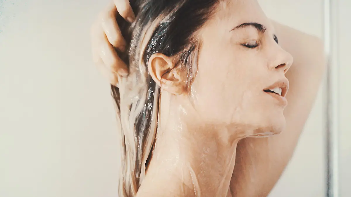 Closeup side view of mid 20's attractive woman taking a relaxing shower after a long stressful day. She's just standing under the waterflow without any soap or shampoo.