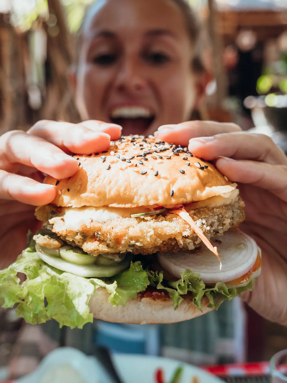 Girl in hipster cafe eating yummy burger. Tropical vacations, eating by the beach