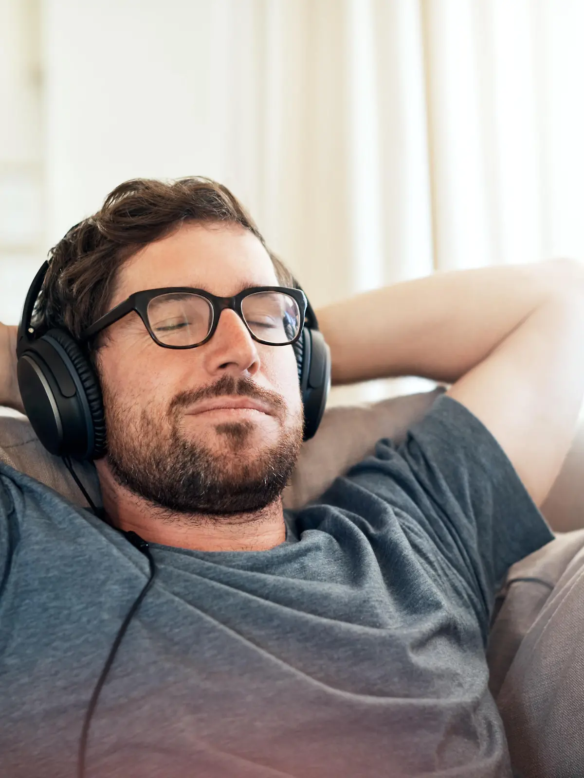 Cropped shot of a handsome young man listening to music on his tablet while relaxing on a sofa at home