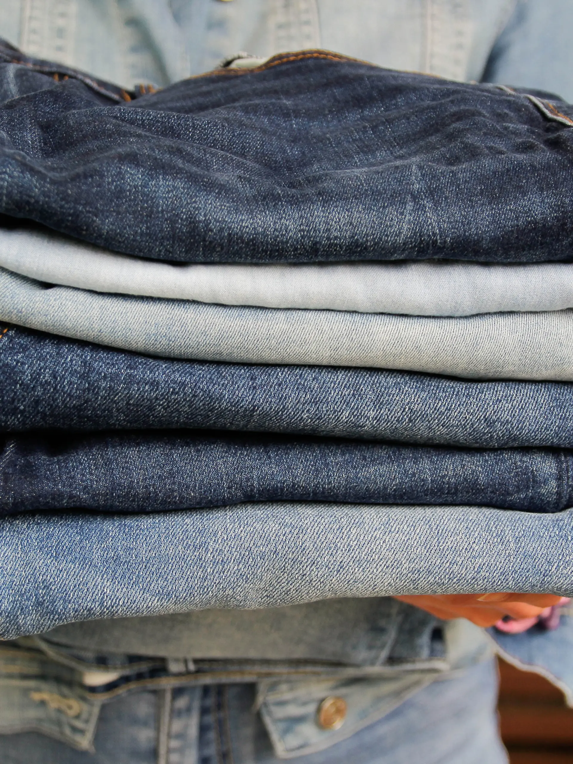 Jeans gestapelt in der Hand einer Frau