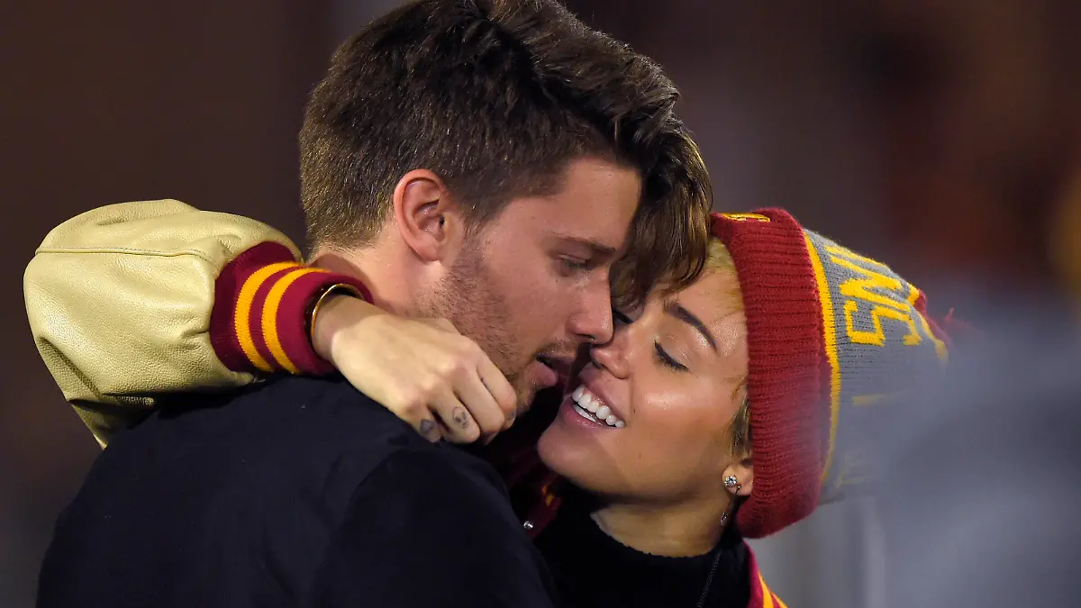 Singer Miley Cyrus, right, puts an arm around Patrick Schwarzenegger as they watch Southern California play California during the second half of an NCAA college football game, Thursday, Nov. 13, 2014, in Los Angeles. (AP Photo/Mark J. Terrill)