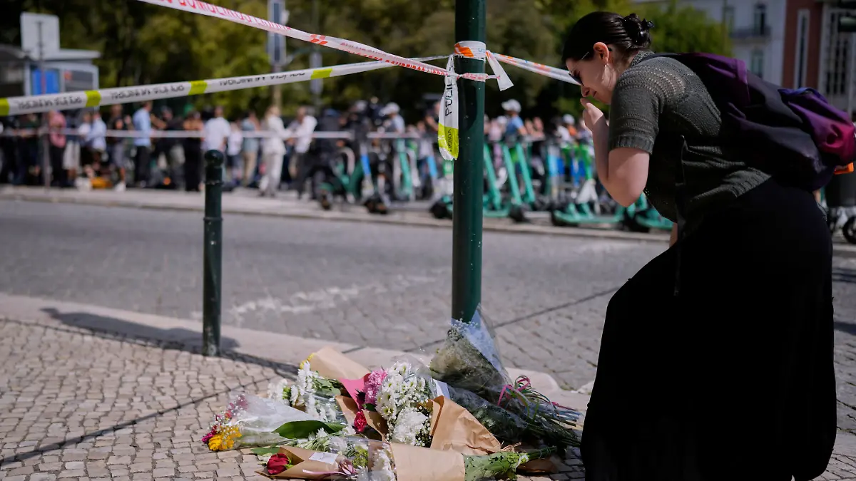Eine Frau legt Blumen an der Stelle ab, an der eine Straßenbahn für Touristen entgleist ist.