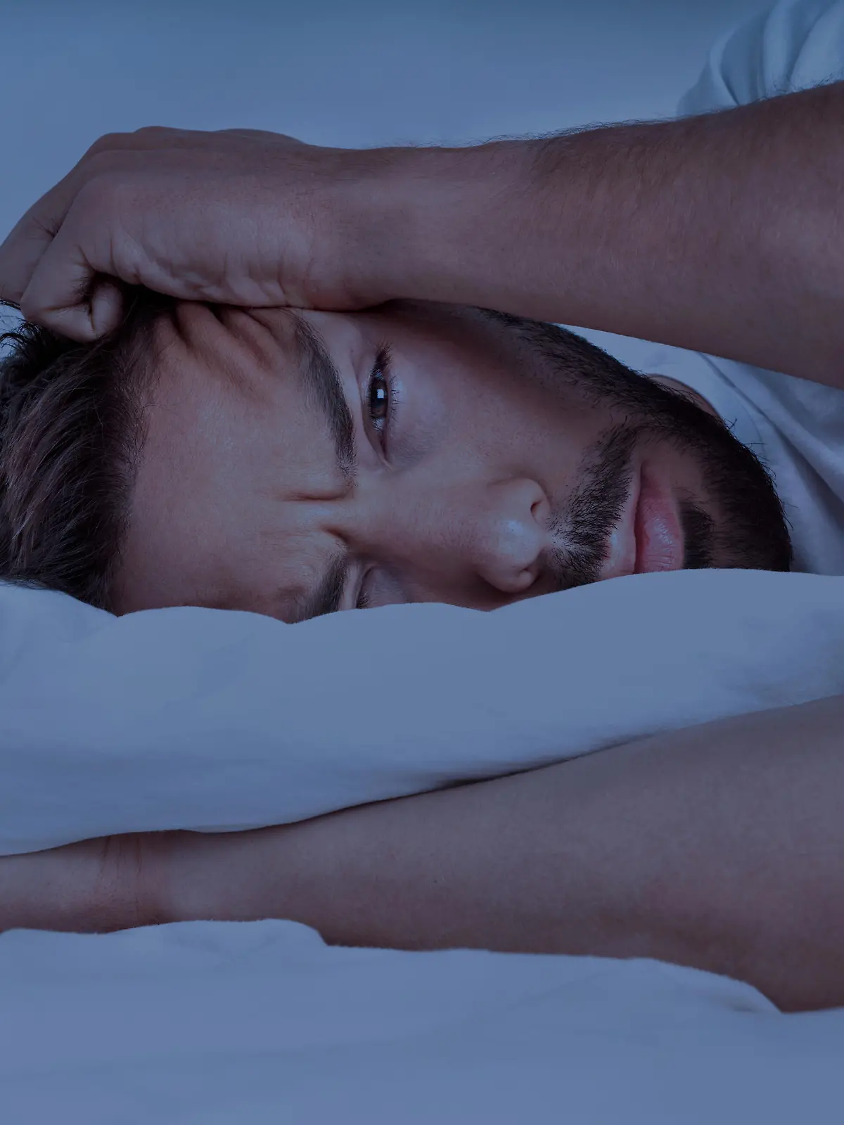 Young man lying in the bed and trying to sleep, can't sleep. Man suffering from insomnia, sleeping problems or sleep disorders. High quality photo