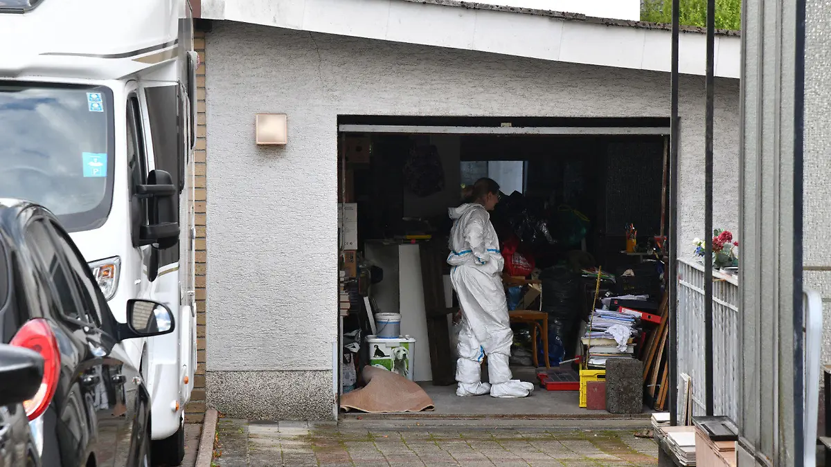 09.08.2023, Saarland, Homburg: Beamte durchsuchen eine Garage im Umfeld eines Gartens, in dem eine Leiche gefunden wurde. Eine verbuddelte Leiche ist im Garten eines Wohnhauses in Homburg (Saarpfalz-Kreis) entdeckt worden. Eine Nachbarin habe die Polizei verständigt, weil sie die Leiche gesehen habe, die bis auf die Füße in der Erde verbuddelt gewesen sei, sagte ein Polizeisprecher. Foto: Beckerbredel/BeckerBredel/dpa - ACHTUNG:Hausnummer gepixelt +++ dpa-Bildfunk +++