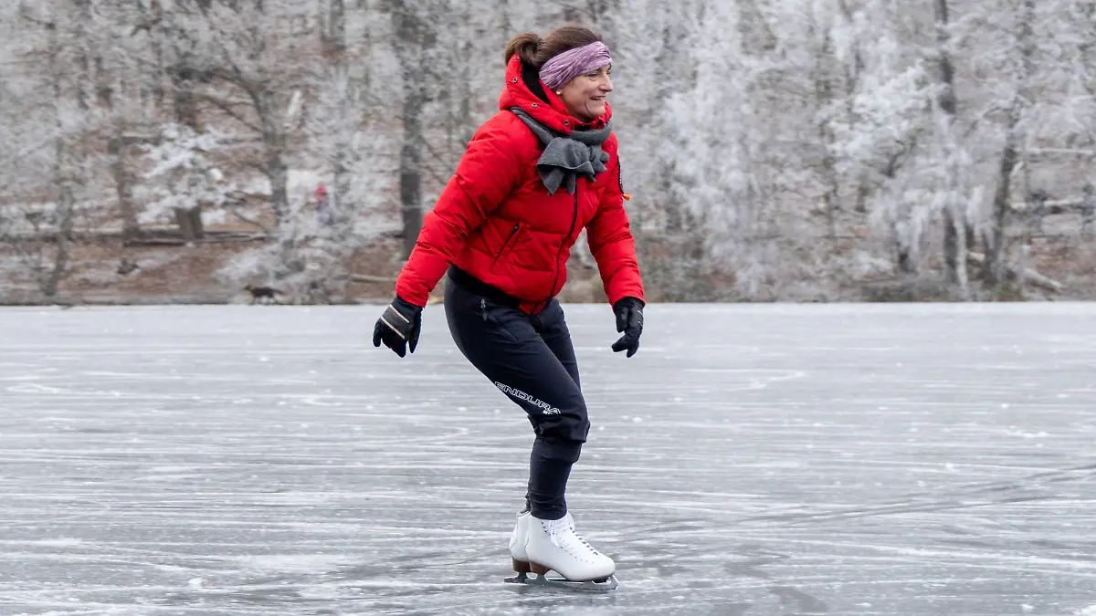Gefrorene Krumme Lanke in Berlin 2002 Berlin, Deutschland - 18. Dezember 2022: Menschen fahren an einem Sonntag Schlittschuh, spielen Eishockey oder rutschen auf der seit gestern zugefrorenen Krummen Lanke See im Bezirk Zehlendorf bei Temperaturen von minus fünf Grad Celsius. Ab nächster Woche soll jedoch Tauwetter einsetzen. Berlin