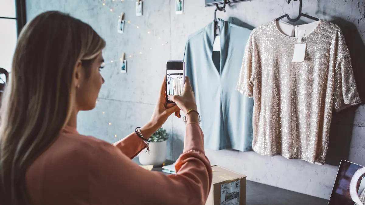 Young woman at online shop. She is owner of small online shop. Photographing new clothes for online store.