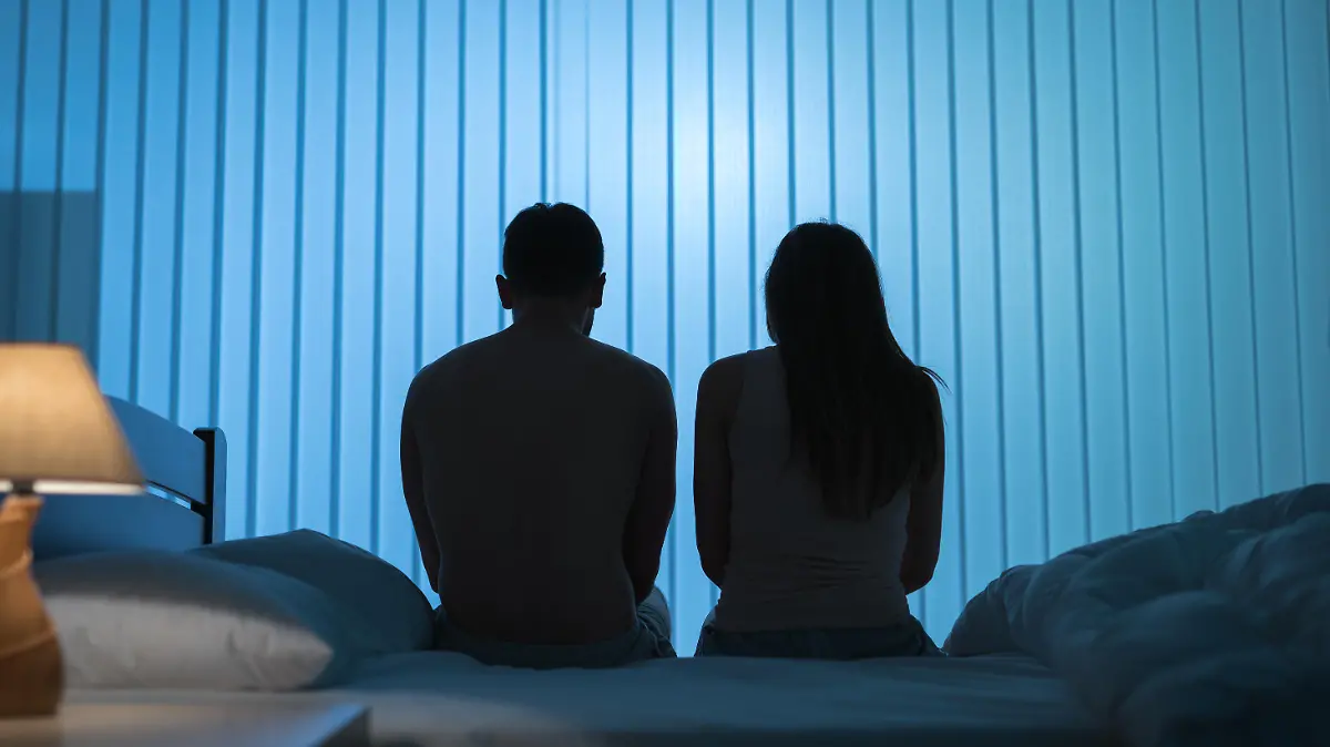 The man and woman sit on the bed. night time