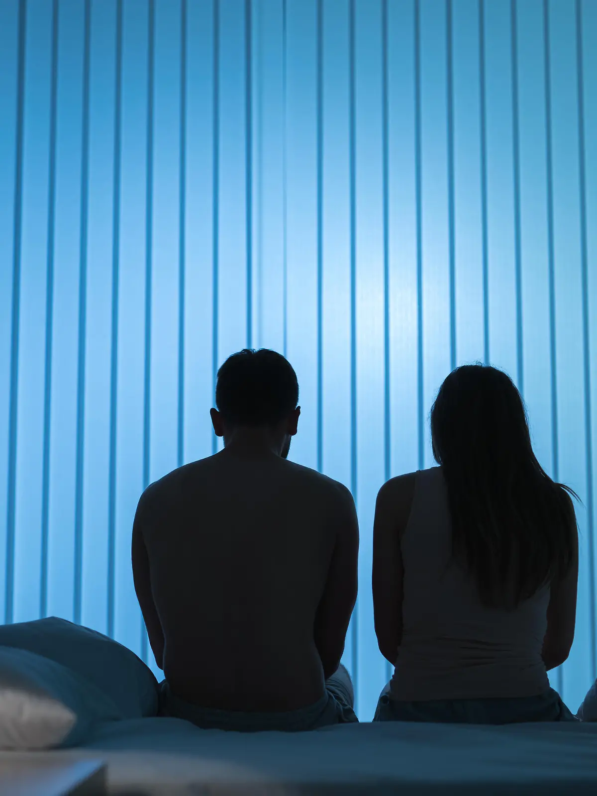 The man and woman sit on the bed. night time