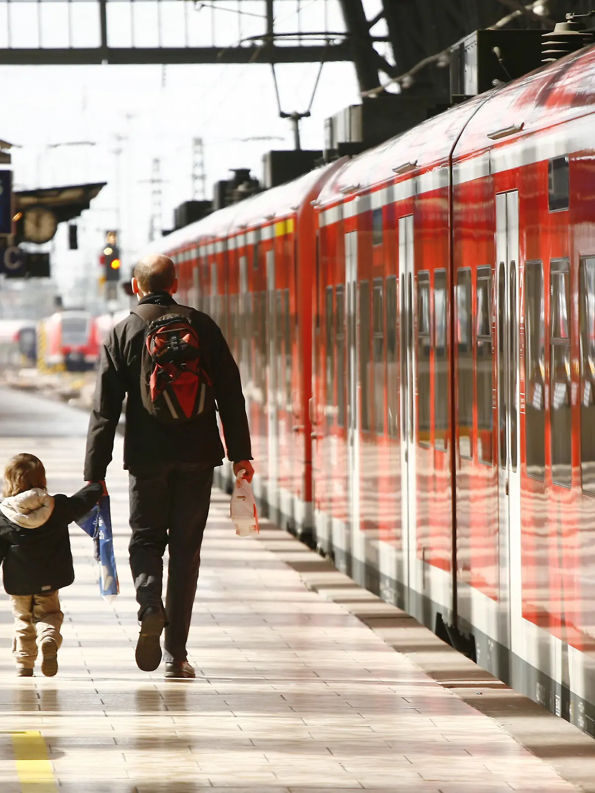 Ein Vater und sein kleiner Sohn gehen über einen Bahnsteig neben einem Zug der Deutschen Bahn zu ihrem Waggon im Hauptbahnhof in Frankfurt am Main am 18.03.2008. Die beiden haben leichtes Gepäck dabei und der Mann hält das Kind an der Hand. Foto: Wolfram Steinberg +++(c) dpa - Report+++