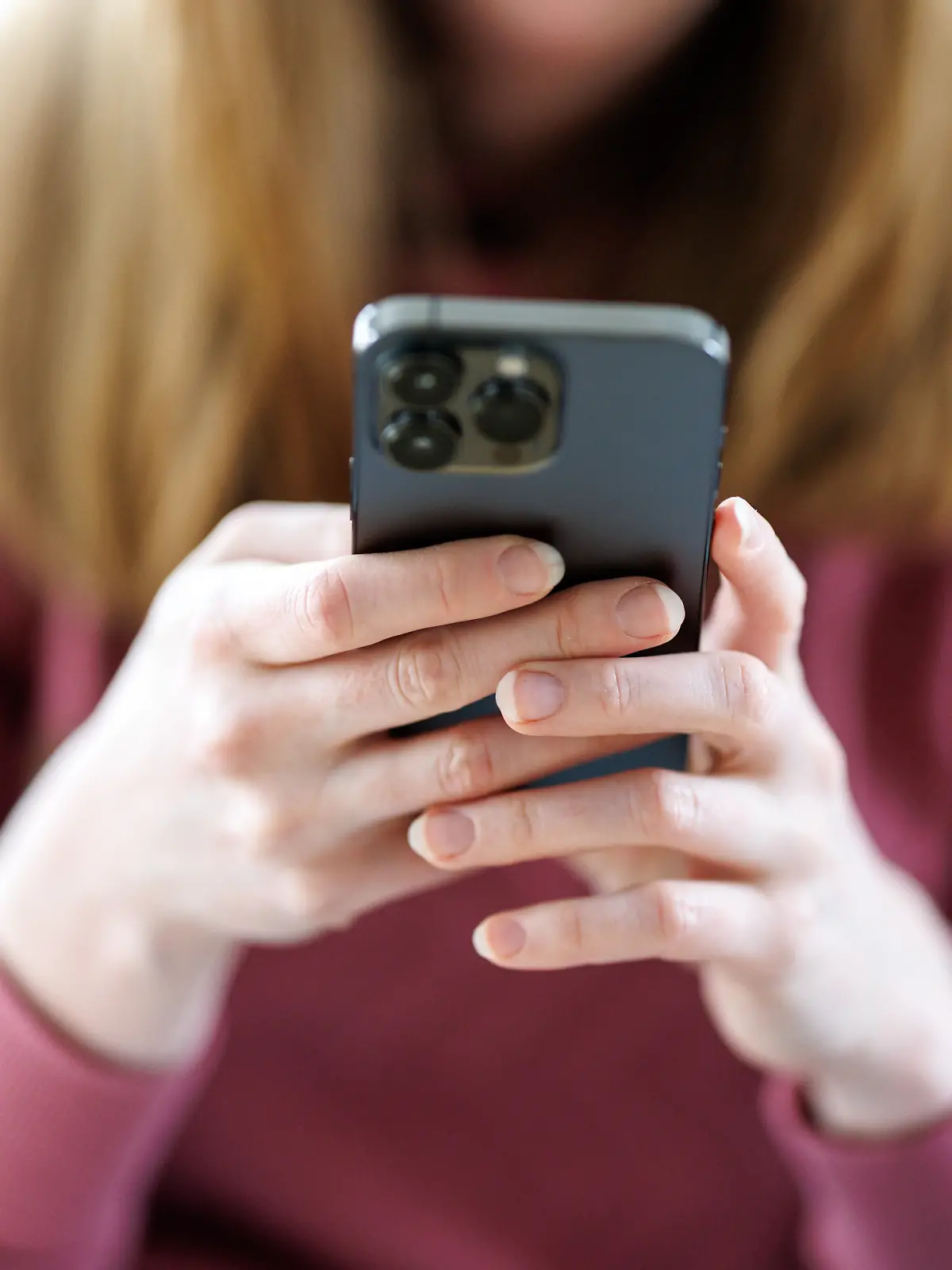 Ein Mädchen benutzt ein Smartphone. Nur ihre Hände sind zu erkennen.