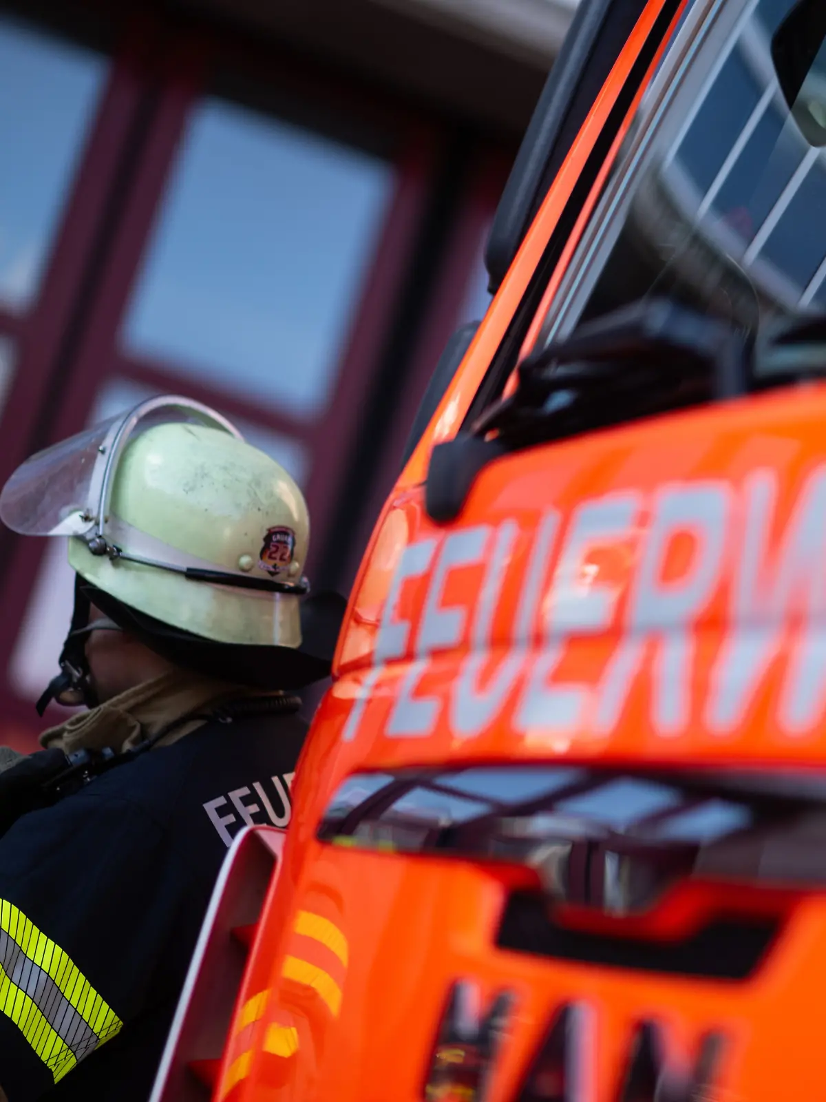 Feuerwehrmann steht neben einem Feuerwehrauto (Symbolbild)