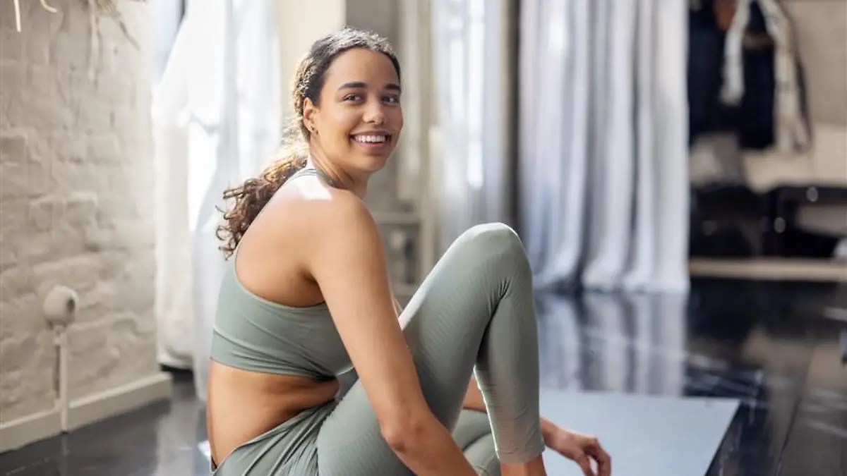 Dunkelhaarige Frau trägt pastellgrünes Sportoutfit. 