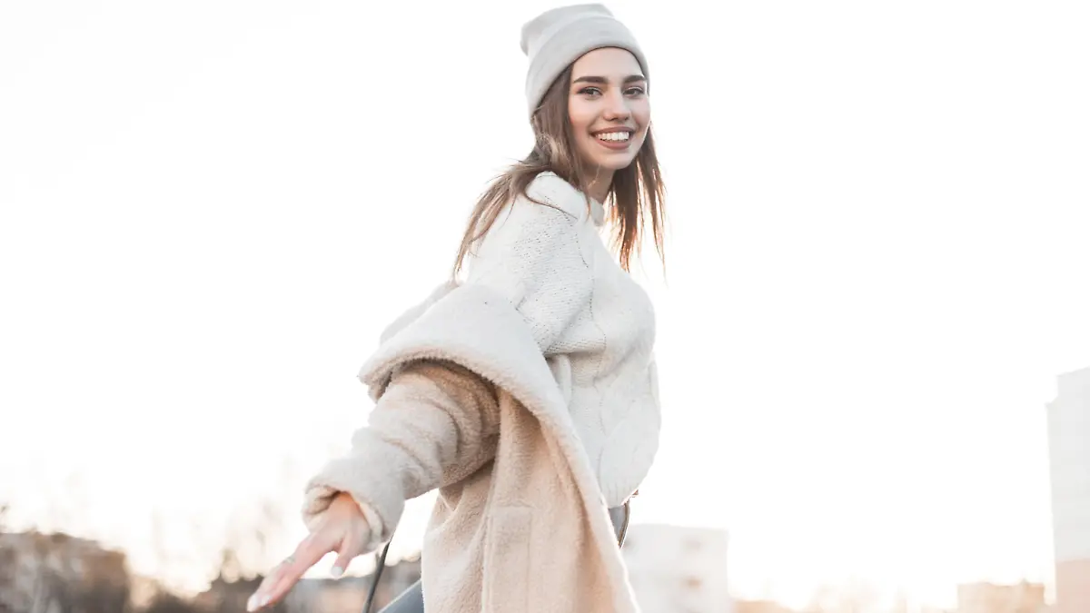 Funny pretty beautiful young woman model in warm fashionable clothes enjoy a walk along the street on a sunny bright winter day. Attractive happy girl with a positive smile posing outdoors. Fashion.