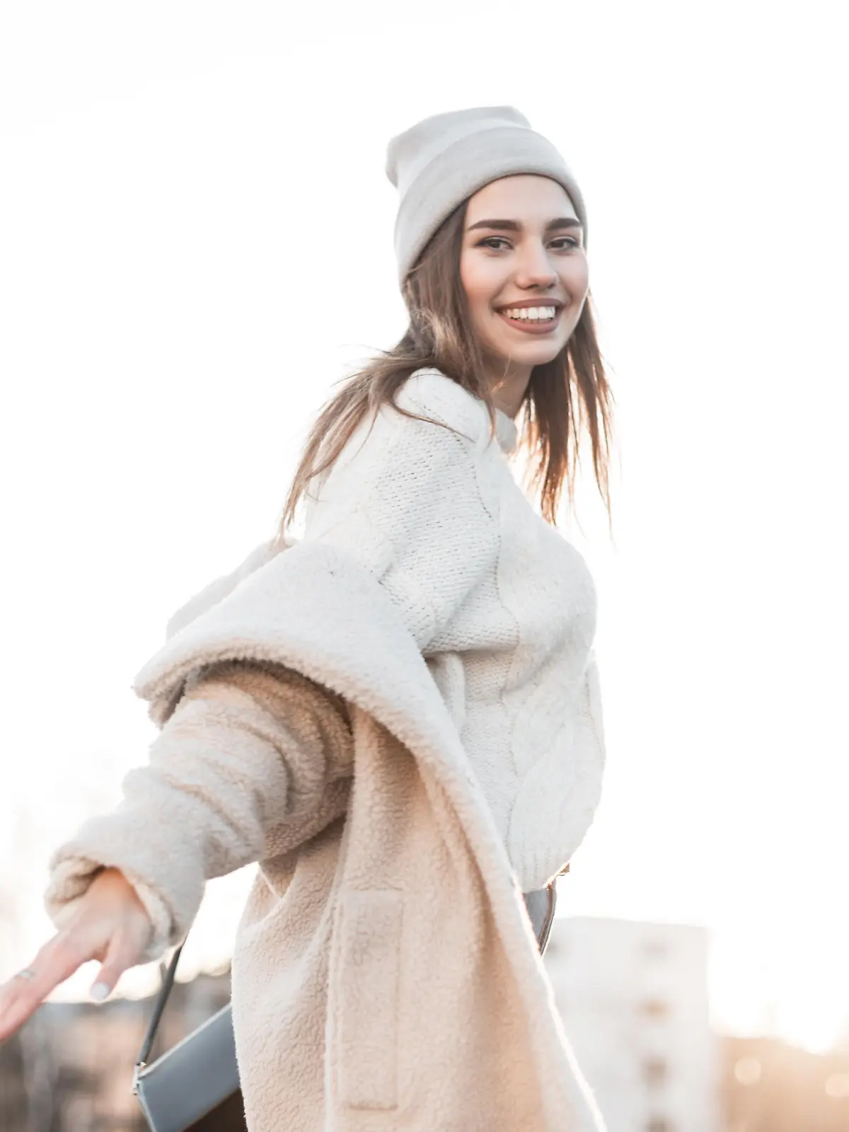 Funny pretty beautiful young woman model in warm fashionable clothes enjoy a walk along the street on a sunny bright winter day. Attractive happy girl with a positive smile posing outdoors. Fashion.
