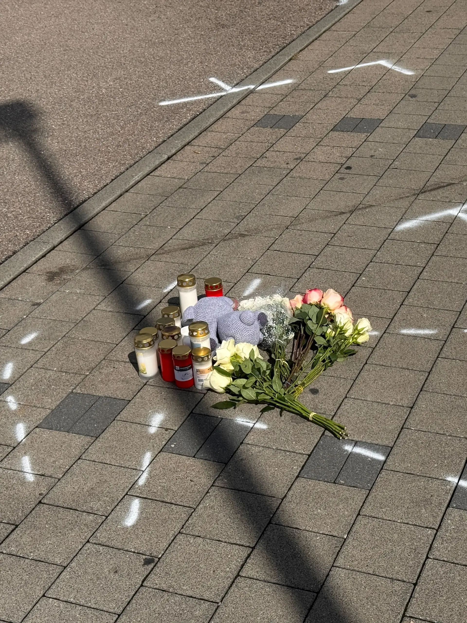 Markierungen mit Sprühfarben und Trauerbekundungen sind zu sehen. Nach einem Streit auf einem Parkplatz soll ein 18-Jähriger einen 12 Jahre alten Jungen in Niedernhall (Hohenlohekreis) mit dem Auto verfolgt, angefahren und tödlich verletzt haben. Der Heranwachsende sei nach der Tat am Donnerstagabend festgenommen worden, teilte die Polizei mit.