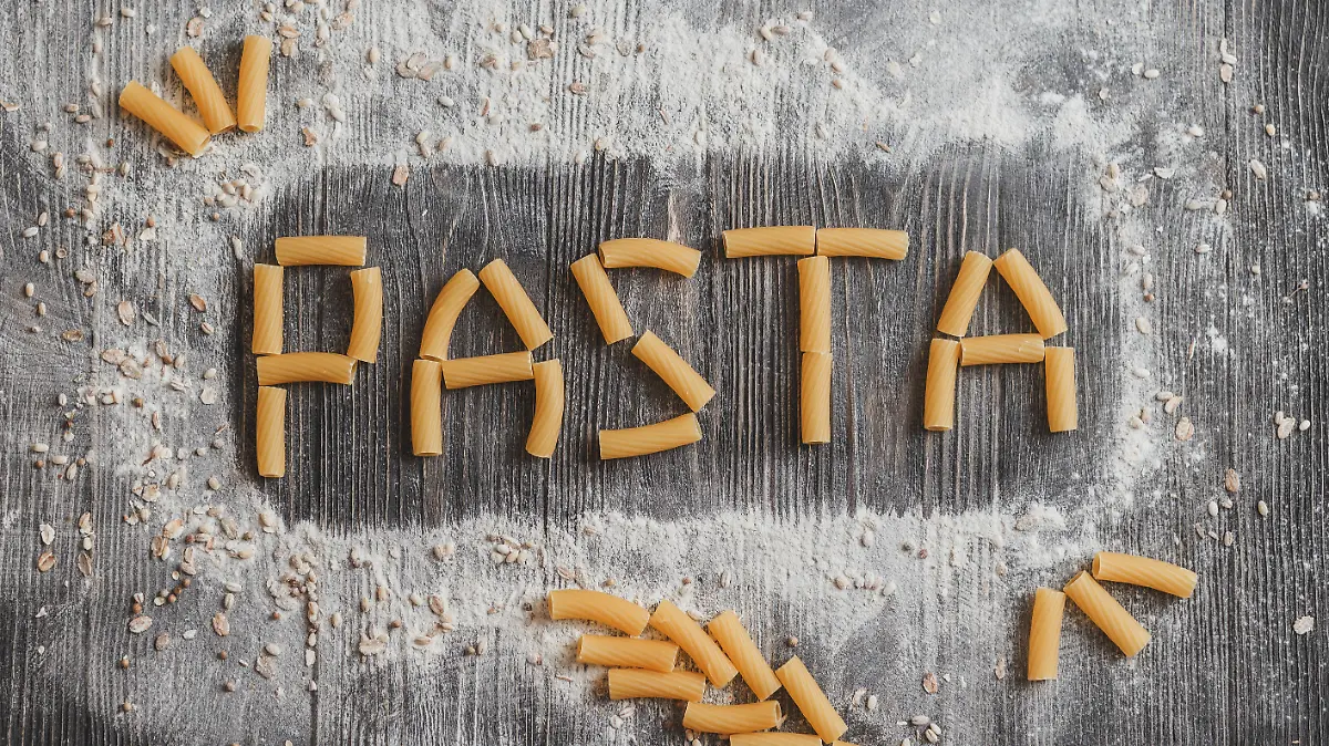 Word pasta, pasta laid out on an old black wooden desk.