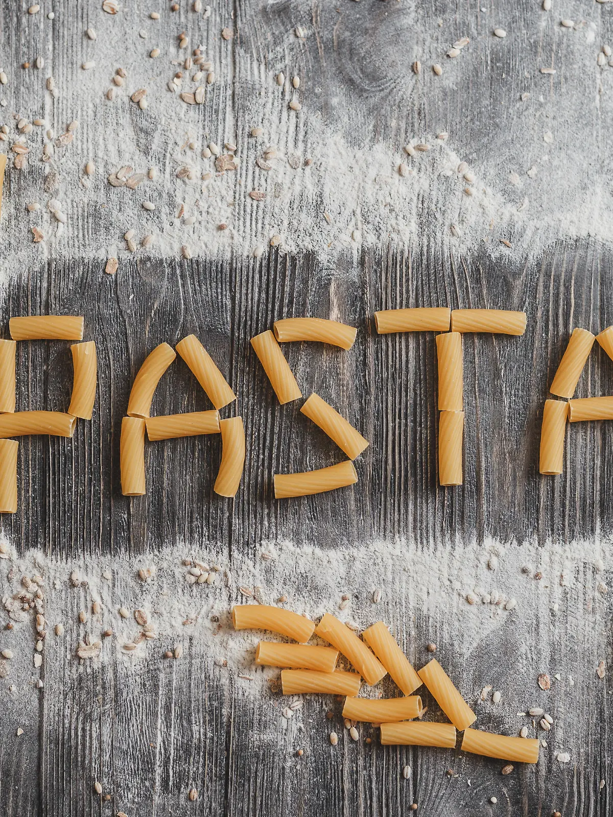 Word pasta, pasta laid out on an old black wooden desk.