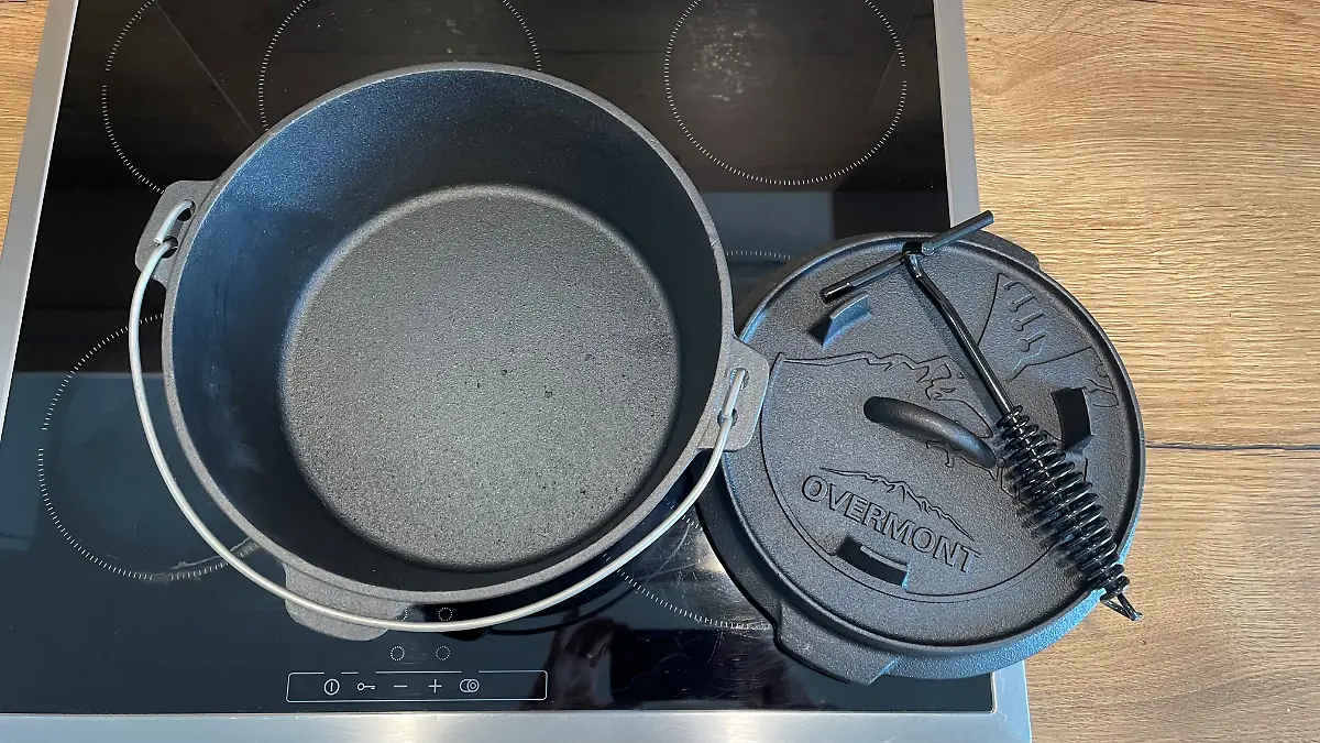Dutch Oven mit Deckel und Deckelzange steht auf dem Herd