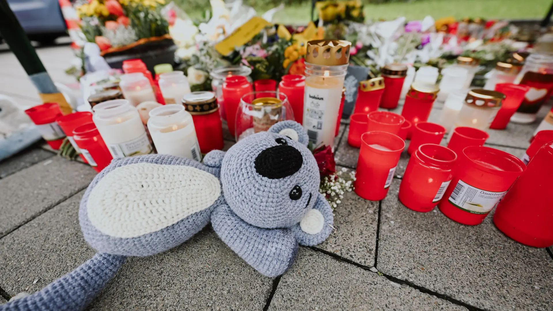 Blumen und Kerzen liegen zum Gedenken an das getötete Kind auf einem Parkplatz eines Supermarktes in der kleinen Gemeinde Niedernhall.