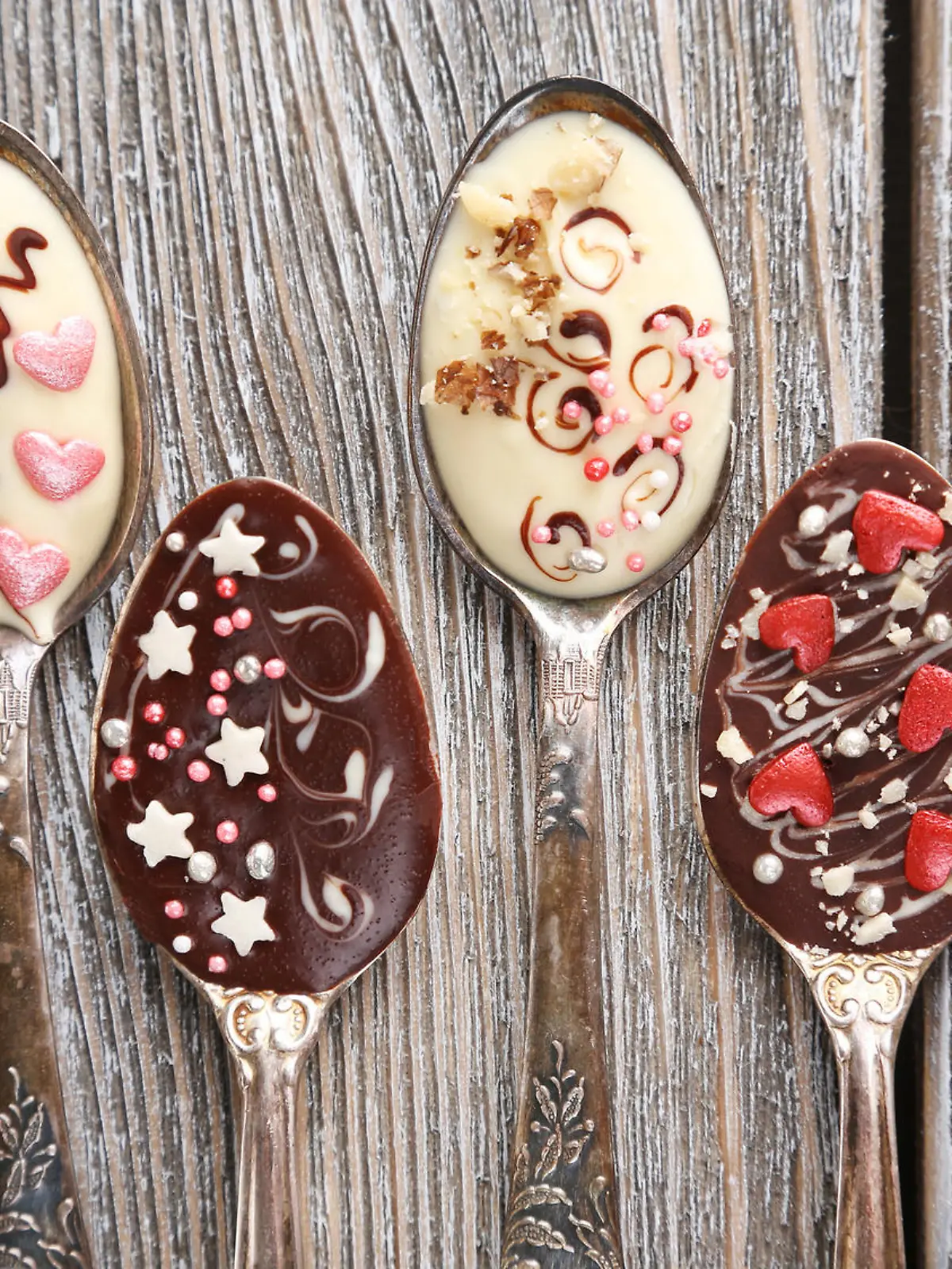 Spoons with tasty chocolate for party on old wooden table