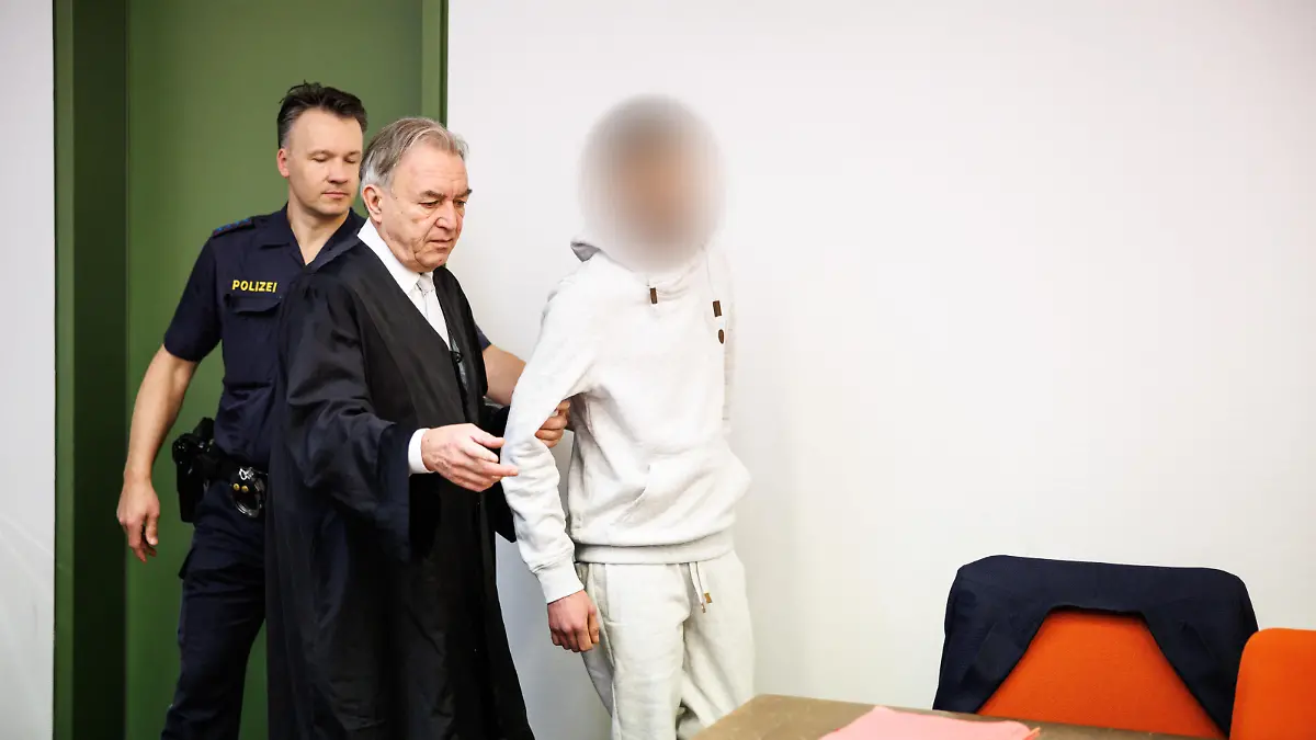 Ein wegen Totschlags angeklagter Mann (r), der seine fünf Wochen alte Tochter in Oberammergau umgebracht haben soll, wird zu Prozessbeginn in einen Gerichtssaal vom Landgericht in München geführt. In der Mitte steht sein Rechtsanwalt Sewarion Kirkitadse. Er soll das Baby geschüttelt und mit dem Kopf gegen einen harten Gegenstand geschlagen haben.
