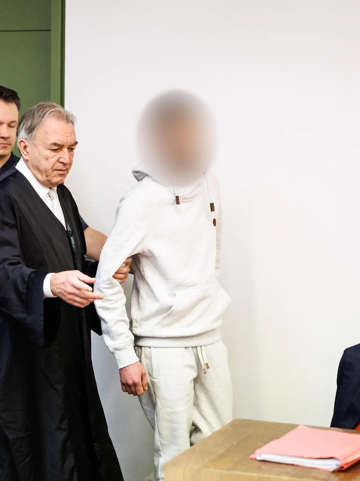 Ein wegen Totschlags angeklagter Mann (r), der seine fünf Wochen alte Tochter in Oberammergau umgebracht haben soll, wird zu Prozessbeginn in einen Gerichtssaal vom Landgericht in München geführt. In der Mitte steht sein Rechtsanwalt Sewarion Kirkitadse. Er soll das Baby geschüttelt und mit dem Kopf gegen einen harten Gegenstand geschlagen haben.