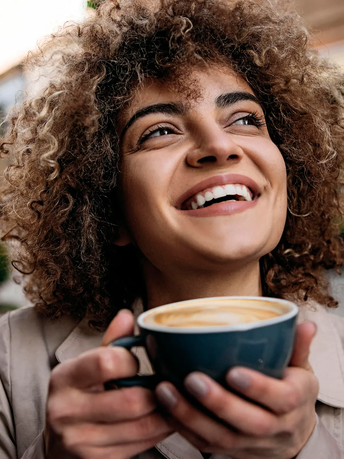 Beautiful young woman smiling drinking cup of coffee outside