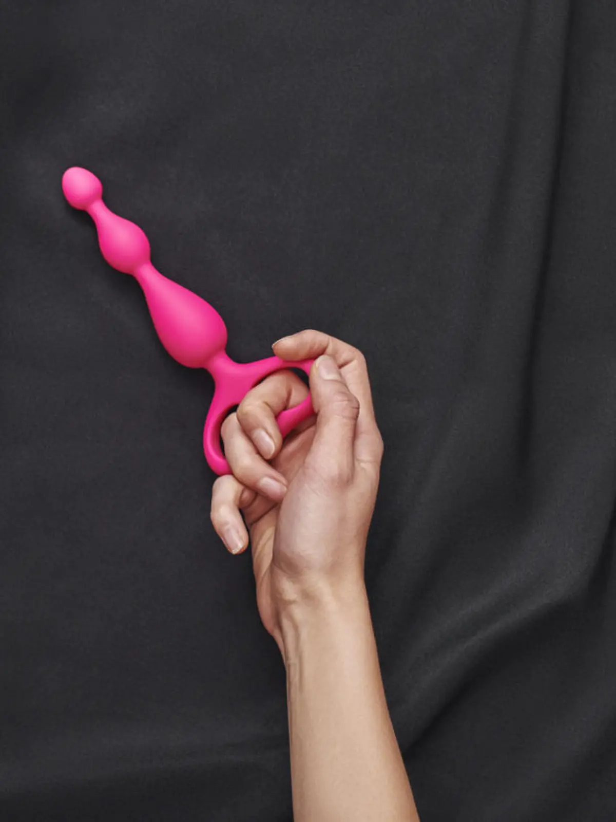 Eine Frau hält ein pinkes Sex-Spielzeug in der Hand