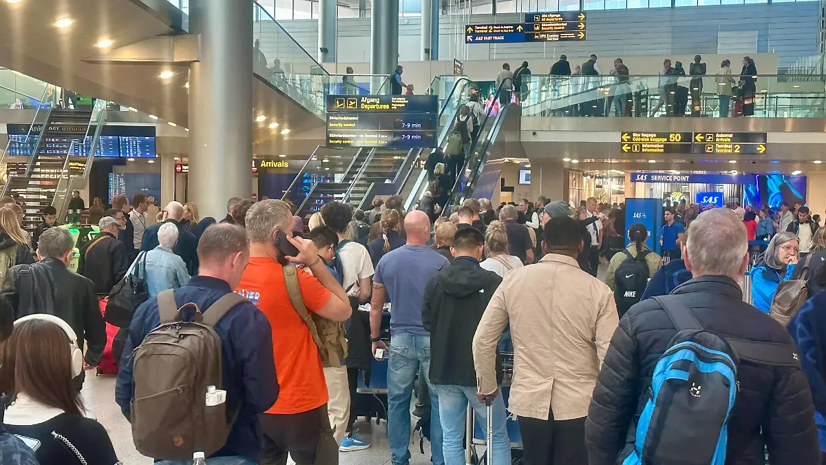 Reisende warten am Flughafen in Kopenhagen an einem Service-Schalter. 
