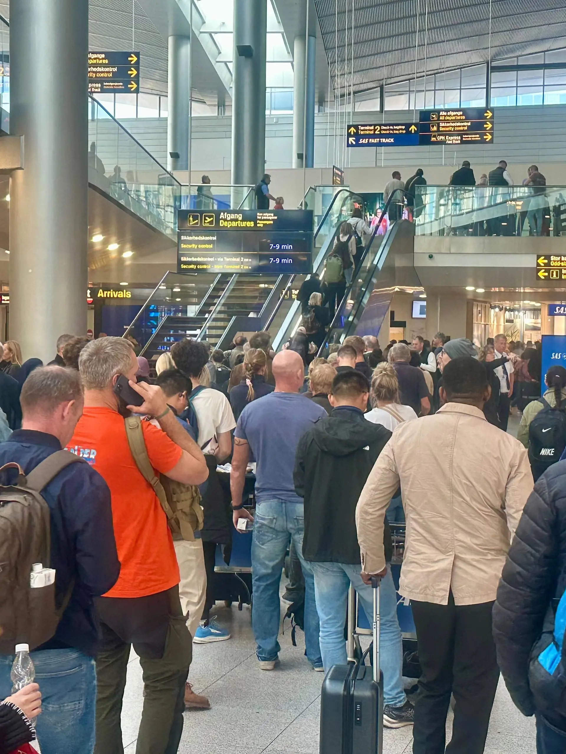 Reisende warten am Flughafen in Kopenhagen an einem Service-Schalter. 