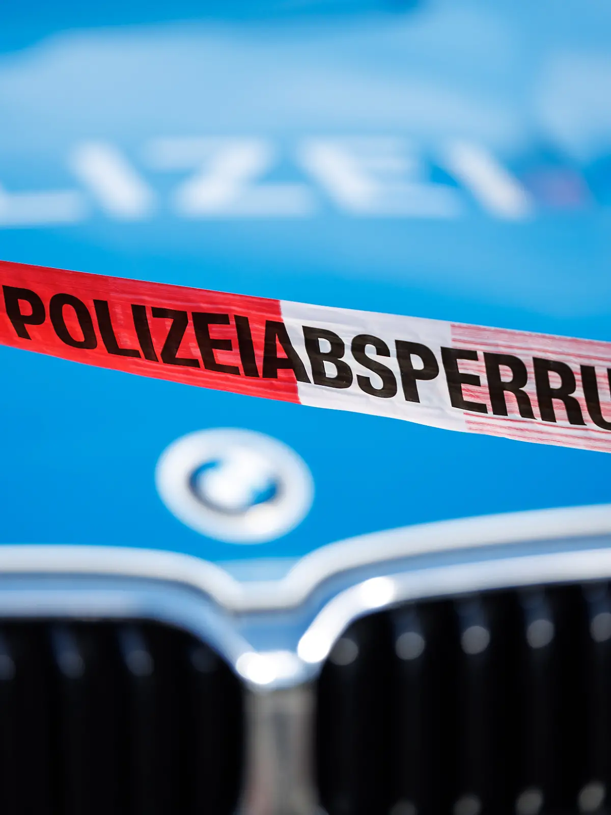 Flatterband mit der Aufschrift Polizeiabsperrung, im Hintergrund ein Einsatzfahrzeug der Polizei.
