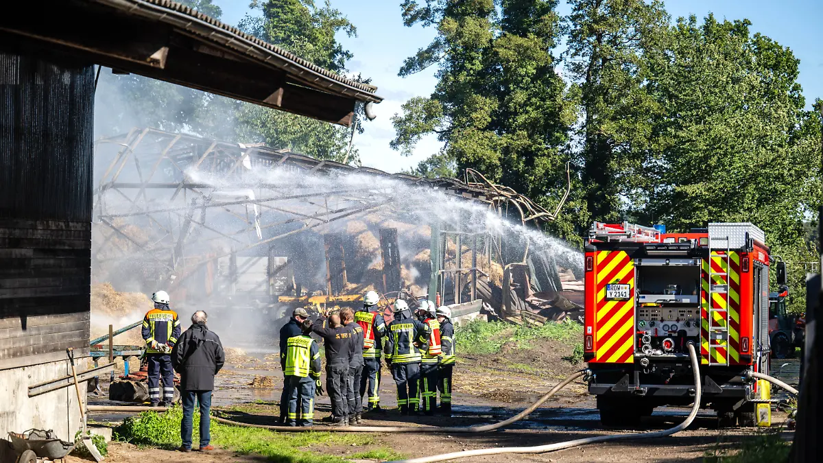 Einsatzkräfte der Feuerwehr löschen einen Brand in Gyhum. Ermittler prüfen, ob er im Zusammenhang mit einem Tötungsdelikt steht, das wenige hundert Meter vom Brandort entfernt verübt wurde.