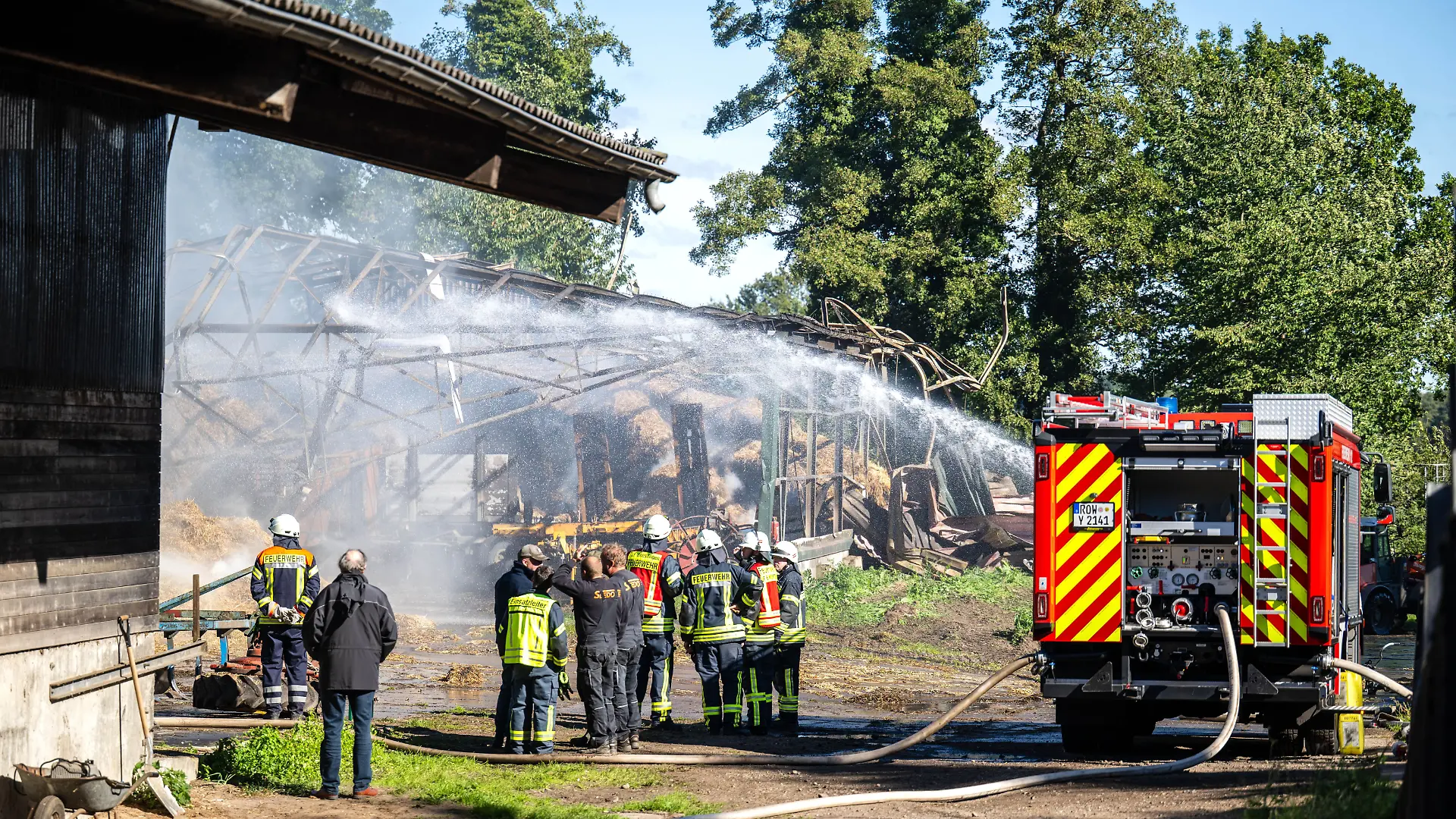 Einsatzkräfte der Feuerwehr löschen einen Brand in Gyhum. Ermittler prüfen, ob er im Zusammenhang mit einem Tötungsdelikt steht, das wenige hundert Meter vom Brandort entfernt verübt wurde.