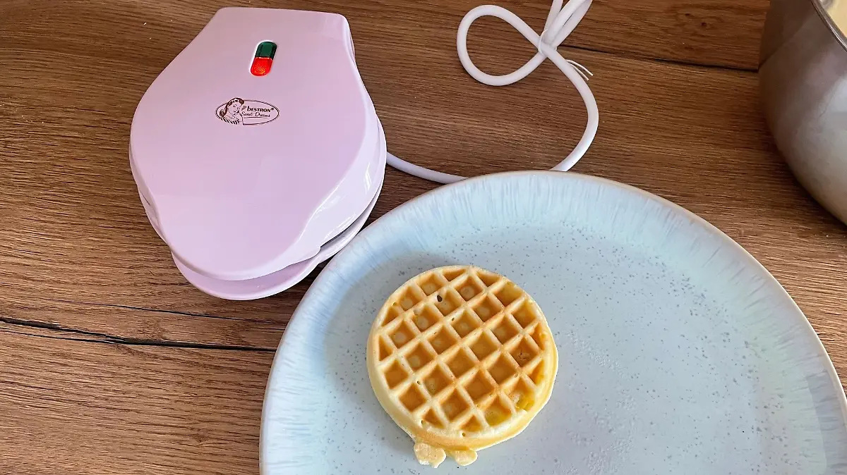 Kleines Waffeleisen mit fertiger Waffel auf dem Tisch 