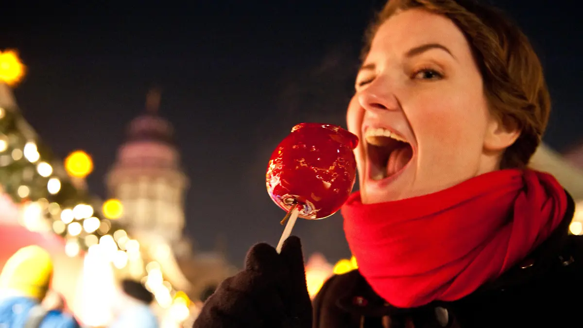 Eine Frau beißt am 21.12.2010 auf dem Weihnachtsmarkt am Gendarmenmarkt in Berlin in einen kandierten Apfel.