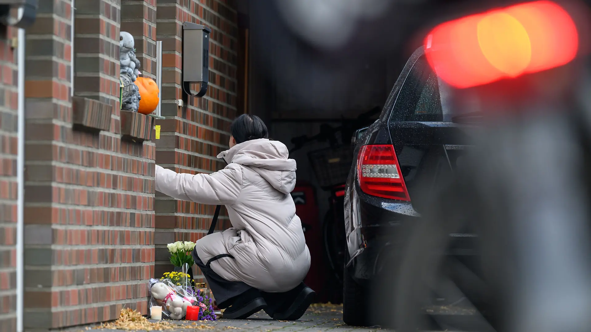 30.09.2025, Niedersachsen, Oldenburg: Angie W., eine Freundin der Familie, kniet vor der Tür des Hauses. Ein Mann soll hier seine Kinder und seine Partnerin erschossen und anschließend sich selbst getötet haben. Foto: Izabella Mittwollen/dpa +++ dpa-Bildfunk +++