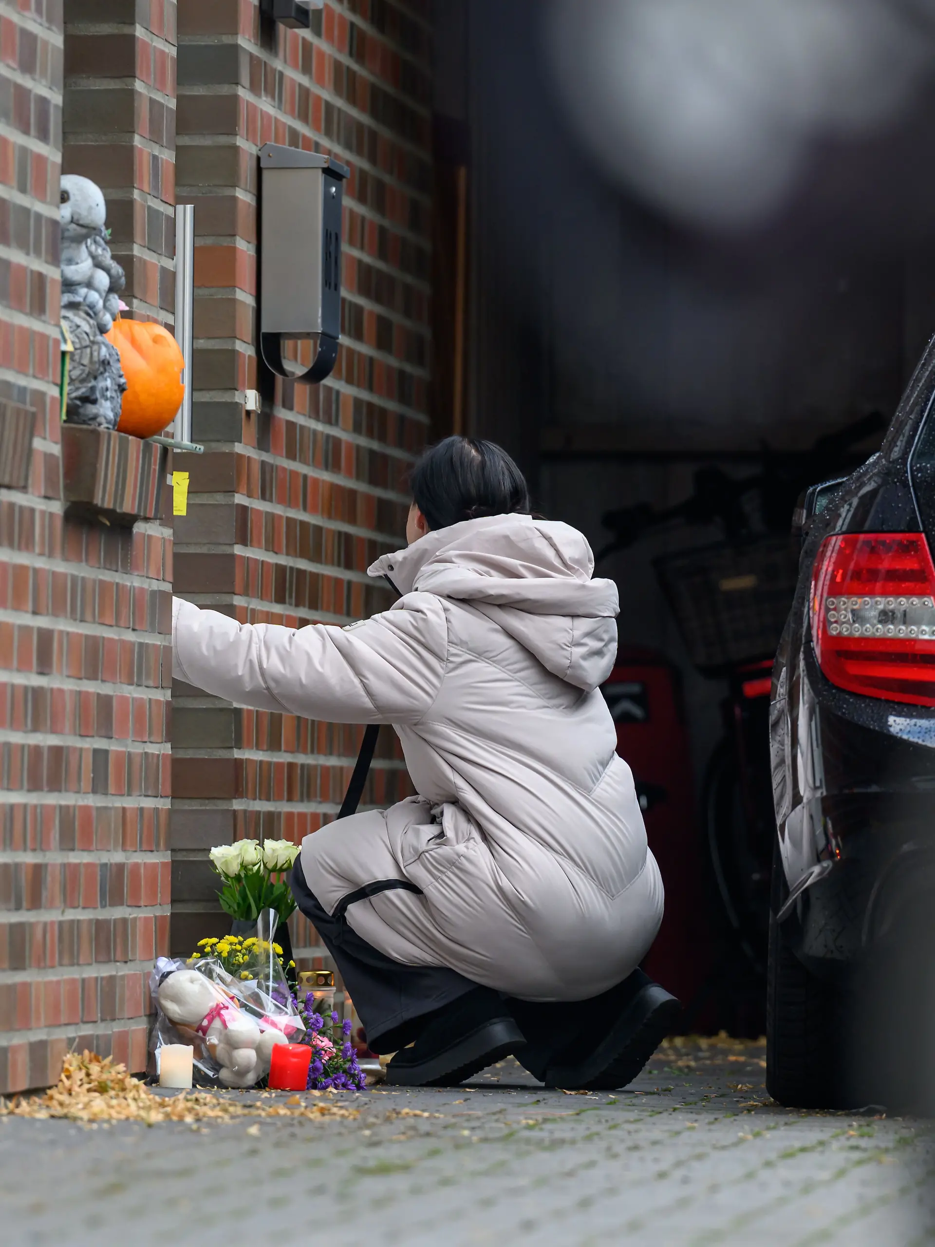 30.09.2025, Niedersachsen, Oldenburg: Angie W., eine Freundin der Familie, kniet vor der Tür des Hauses. Ein Mann soll hier seine Kinder und seine Partnerin erschossen und anschließend sich selbst getötet haben. Foto: Izabella Mittwollen/dpa +++ dpa-Bildfunk +++