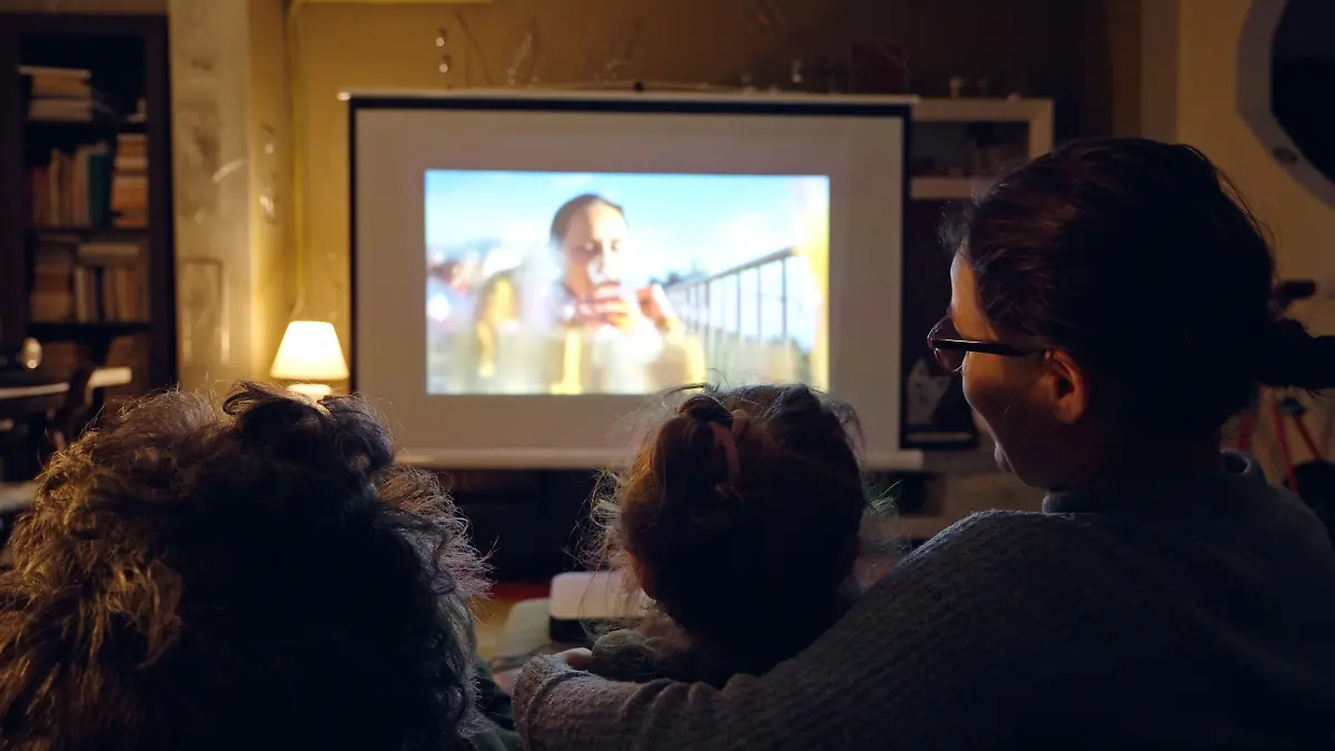Familie sitzt auf der Couch und guckt einen Film über einen Beamer.