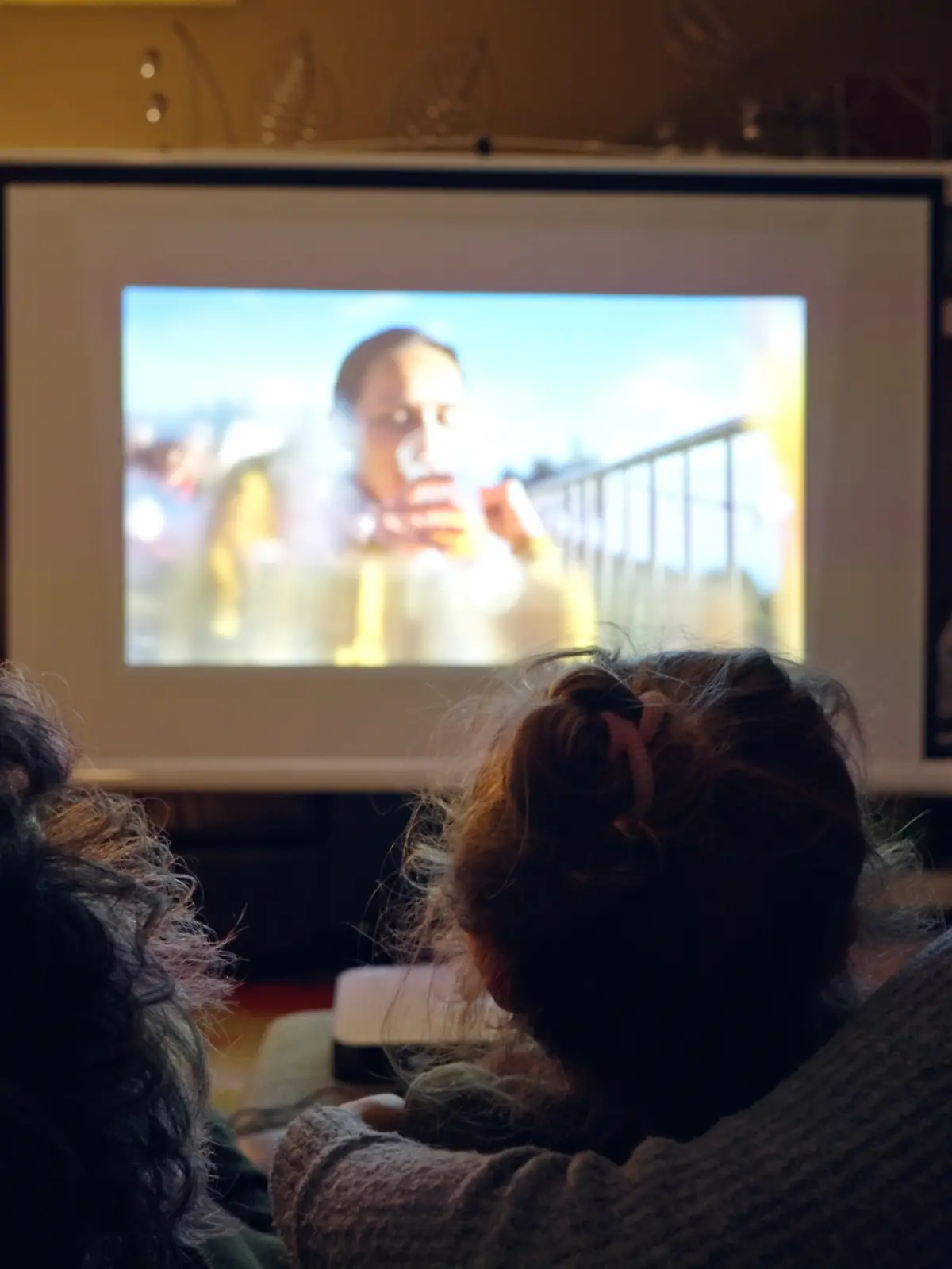 Familie sitzt auf der Couch und guckt einen Film über einen Beamer.
